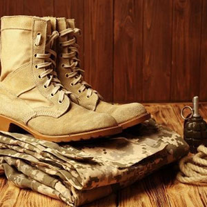 Military boots, uniform and a grenade placed on a table- Moss Bollinger LLP