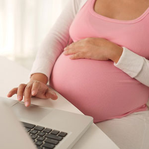 A pregnant woman working on her laptop- Moss Bollinger LLP