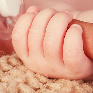 A newborn baby's hand in her mother’s hand - Moss Bollinger LLP