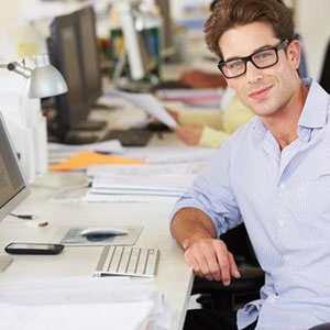 A focused man wearing glasses sits at a desk, engrossed in his work on a computer- Moss Bollinger LLP