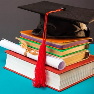 A graduation cap and books neatly arranged on a blue table- Moss Bollinger LLP