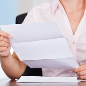 A woman holding a piece of paper, possibly reading or writing something important- Moss Bollinger LLP