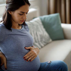 A pregnant woman sitting on a couch- Moss Bollinger LLP