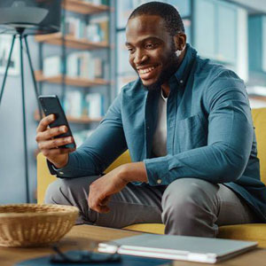 A man sitting on a couch using cell phone- Moss Bollinger LLP