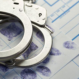 Handcuffs placed on a paper with fingerprints, indicating evidence or a crime scene- Moss Bollinger LLP