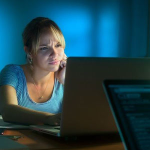 A woman sitting at a desk, focused on her laptop, working diligently- Moss Bollinger LLP