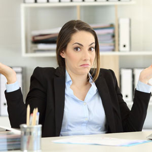 A professional woman seated at her desk, wearing a business suit, with her hands extended in front of her- Moss Bollinger LLP