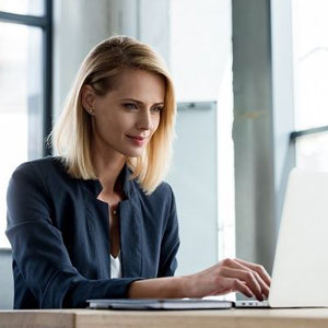 A woman sitting at a table, focused on her laptop- Moss Bollinger LLP