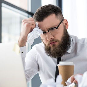 A bearded man wearing glasses sits at a desk, focused on his laptop- Moss Bollinger LLP