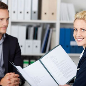 A man and woman sitting at a desk, reviewing a folder- Moss Bollinger LLP