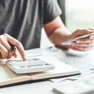 A person calculating finances with a card and calculator on documents- Moss Bollinger LLP