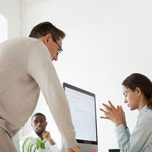 Two individuals discussing near a computer in an office setting- Moss Bollinger LLP