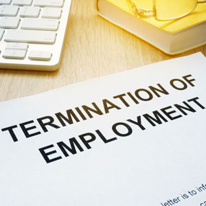 Termination document on wooden surface with keyboard and yellow sticky note pad in office setting- Moss Bollinger LLP