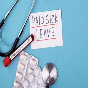 Medical essentials on teal surface: PAID SICK LEAVE note, shiny stethoscope, COVID TEST tube, pill blister pack- Moss Bollinger LLP
