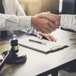 Two professionals shaking hands in agreement during a business meeting - Moss Bollinger LLP