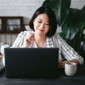 Asian woman focused on her work, typing on a laptop in a office - Moss Bollinger LLP