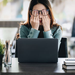 woman wearing glasses sits at a desk, her eyes covered by the glasses - Moss Bollinger LLP