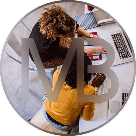 Two women sitting in chair engrossed in their work on laptops - Moss Bollinger LLP