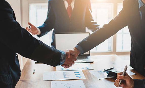 Business people shaking hands over a table - Moss Bollinger LLP