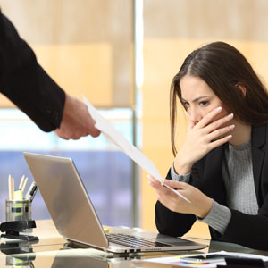 A woman in a business suit receiving a paper related to a wrongful termination letter from the office. - Moss Bollinger LLP